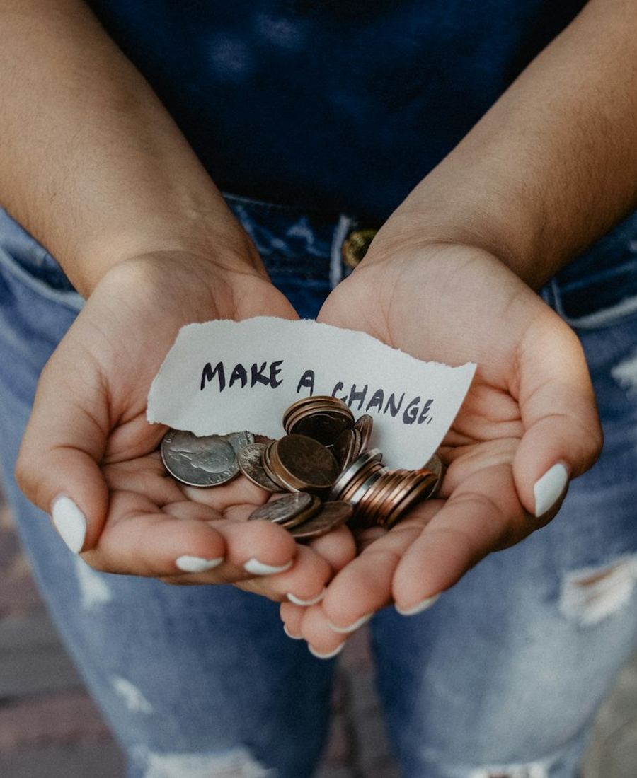 Open hands holding coins and a note that reads make a change