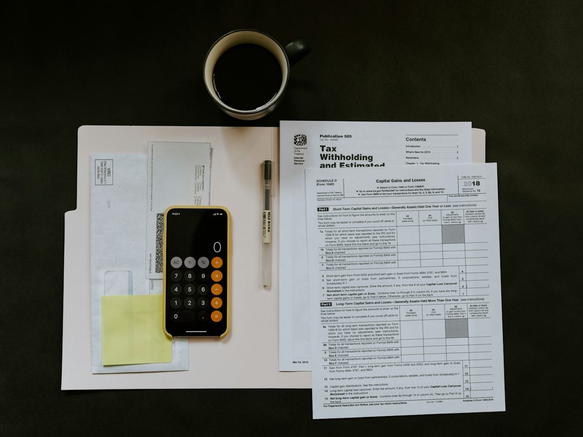Tax forms, a calculator and a pen laid out for review
