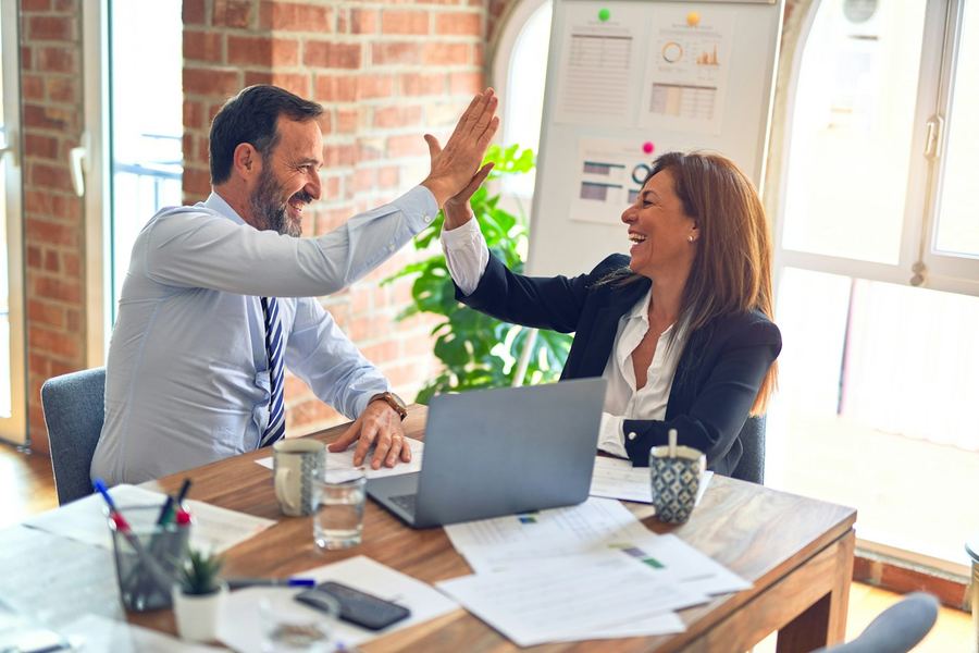 Two colleagues celebrating progress at a desk